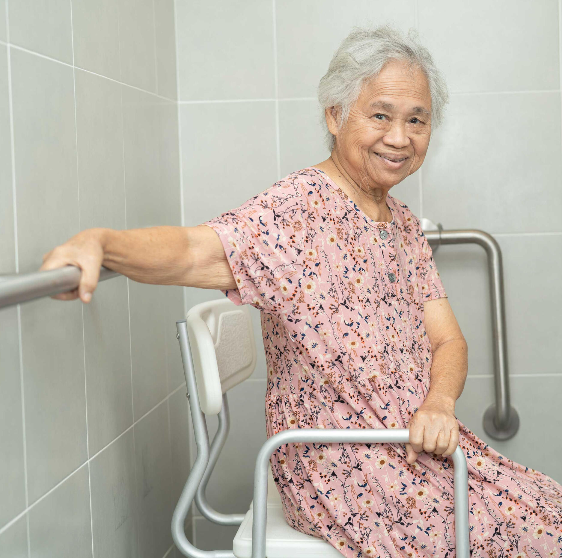 elderly woman using grab bars in bathroom